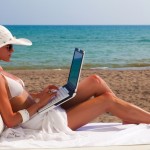 woman on beach working on  laptop against the sea