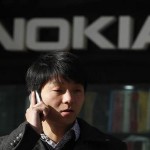 A man using his mobile phone walks under a Nokia logo in Shanghai