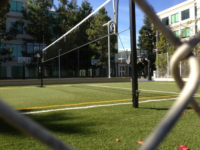 behind-the-chain-link-fence-is-a-volleyball-court-with-astroturf