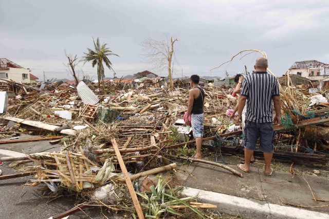 Survivors assess the damage after super Typhoon Haiyan battered Tacloban city, central Philippines