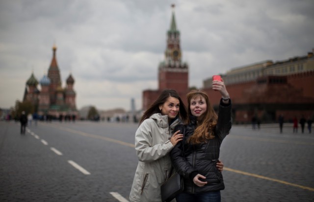 FILE - In this Monday, Oct. 6, 2014 file photo, two young women pose for a selfie on Red Square with St. Basil's Cathedral, left, and the Spasskaya Tower, right in Moscow, Russia. Alarmed by the number of Russians who have been killed while taking photos of themselves with smartphones, Russian police have started a new campaign called "Safe Selfies." The instructions issued Tuesday, July 7, 2015 warn against standing on railroad tracks, climbing onto roofs or posing with a gun or a tiger. (AP Photo/Alexander Zemlianichenko, File)