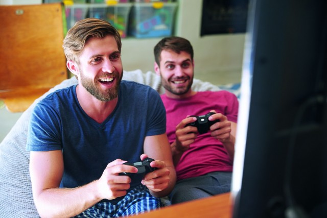 Two Male Friends In Pajamas Playing Video Game Together