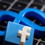 A 3D printed Facebook's new rebrand logo Meta and Facebook logo are placed on laptop keyboard in this illustration