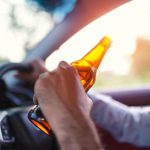 0_Drunk-asian-young-man-drives-a-car-with-a-bottle-of-beer