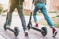 Close up of people couple using electric scooter in city park - Millenial students riding new modern ecological mean of transport - Green eco energy concept with zero emission - Warm sunshine filter