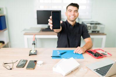 Cheerful technician holding a brand new phone